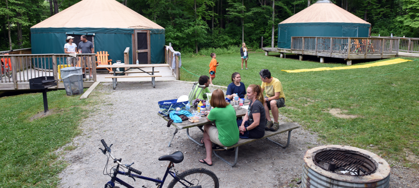 Campers sit around a picnic table near the Yurts at Addison Oaks