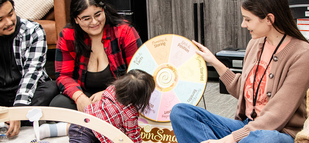 A group of people and a child with a colorful spinning wheel in a cozy room.