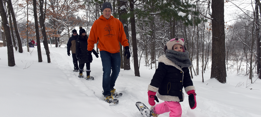 Three adults and one child using snowshoes during the winter on the Wint Nature Trail