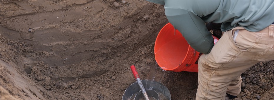 Person pouring water into a circular mold.
