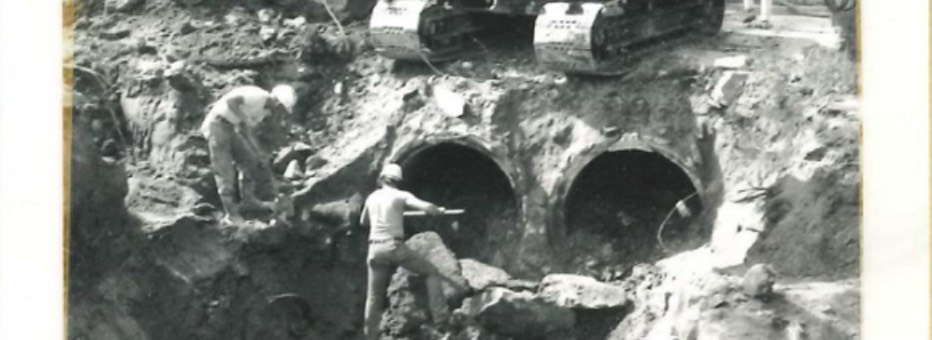 Historic photo of workers digging around two water pipes